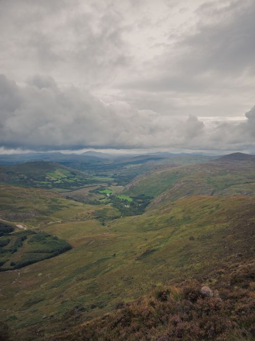 Free A breathtaking view of Ireland's lush green hills beneath dramatic cloudy skies, showcasing nature's untouched beauty. Stock Photo