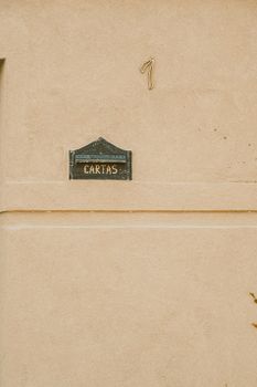 Old wall with a vintage letter box marked 'Cartas' and the number seven.