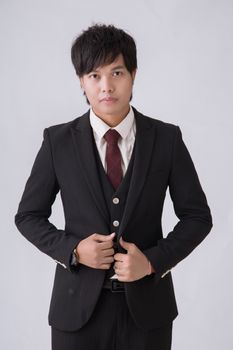 Portrait of a confident young man in a formal suit with a neutral background.