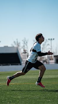 A young athlete in motion during a sprint training session on an outdoor sports field under clear skies.