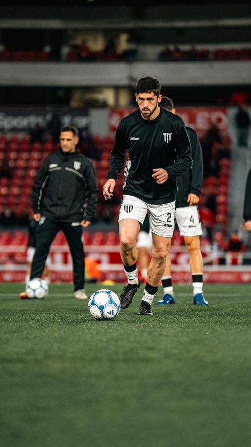 Free Soccer players in black jerseys warming up on a stadium field pre-match. Stock Photo