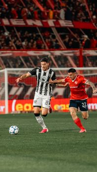 Two soccer players in action during a competitive match in a packed stadium.