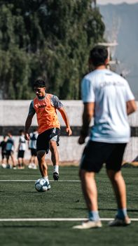 Dynamic soccer practice with young adults playing on a sunny day outdoor field.
