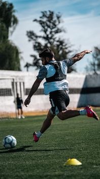 Dynamic action shot of a soccer player striking a ball during practice.