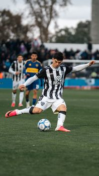 Male soccer player in action on field during daylight, showcasing athletic skills in intense match.