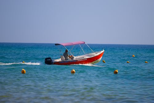 Free A vibrant red motorboat glides through clear blue waters in Greece under a sunny sky. Stock Photo