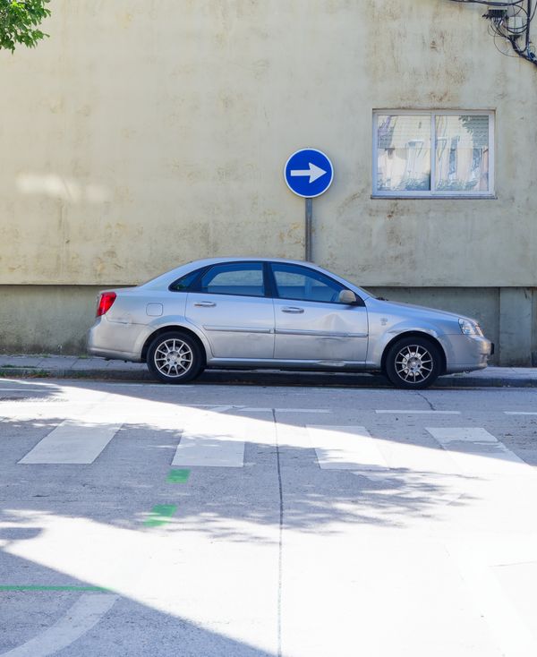 Voiture argentée garée près d'un mur, panneau bleu de virage à droite, à Irun, au Pays basque