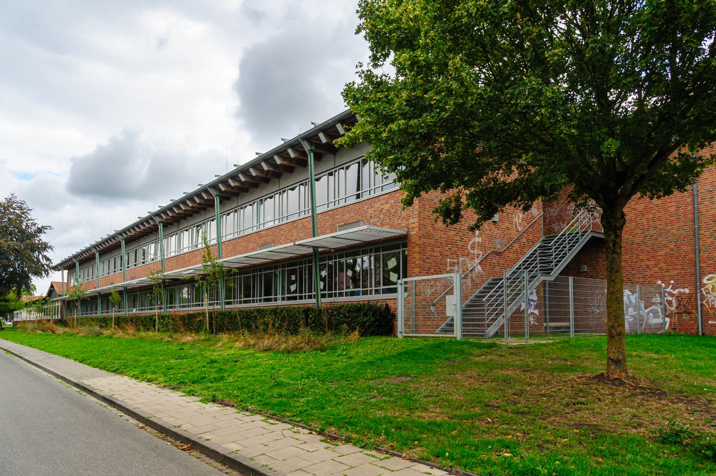 A long brick school building beside a tree and grass