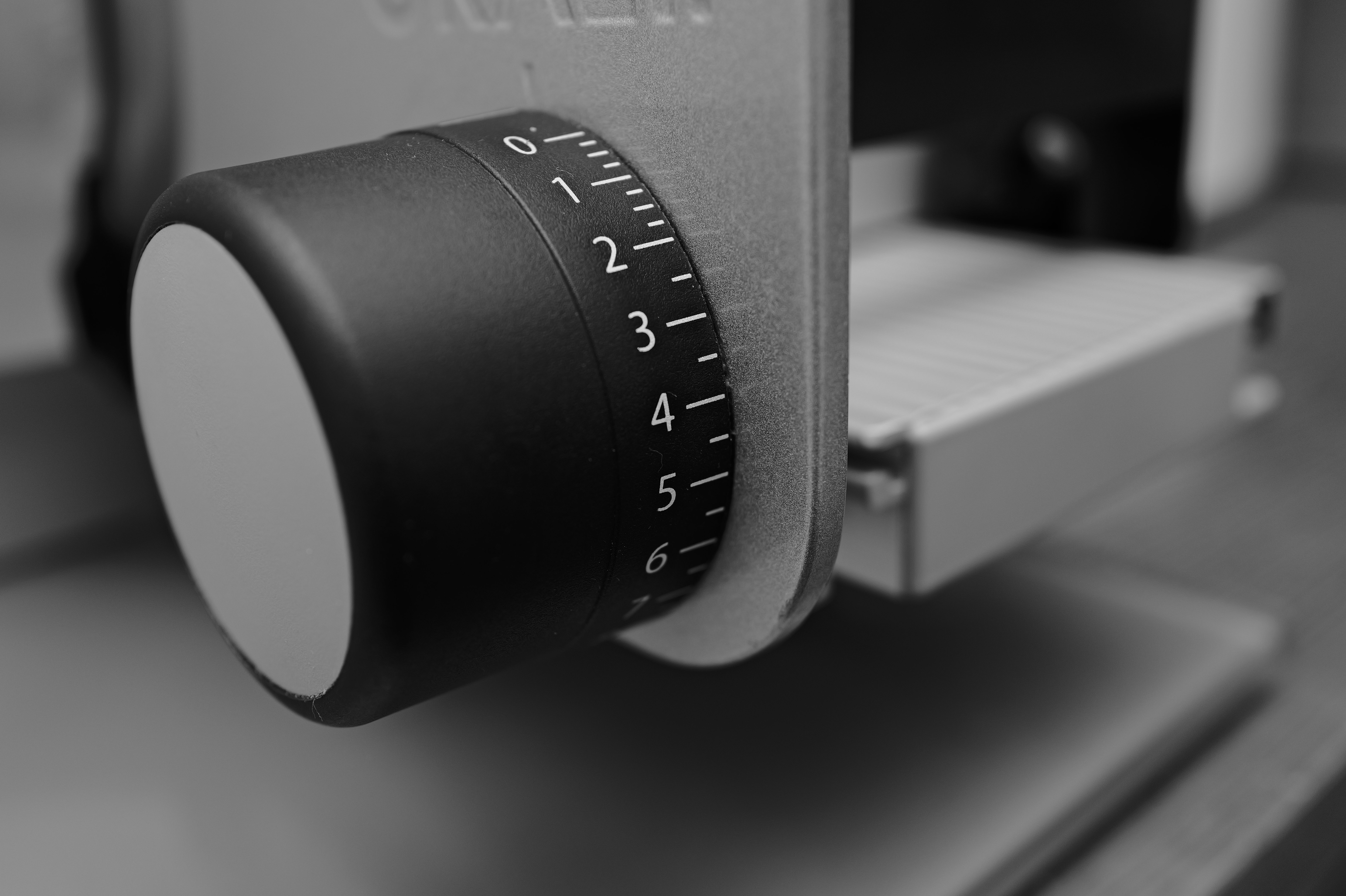 Detailed monochrome close-up of a kitchen appliance knob with numbers, capturing industrial design.