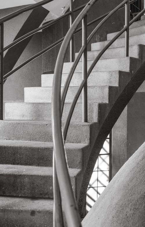 Free Monochrome photo highlighting a concrete spiral staircase with a curved railing in the Voortrekker Monument. Stock Photo
