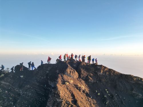 Free A group of hikers capturing the morning view atop Mount Rinjani's summit with clear skies. Stock Photo
