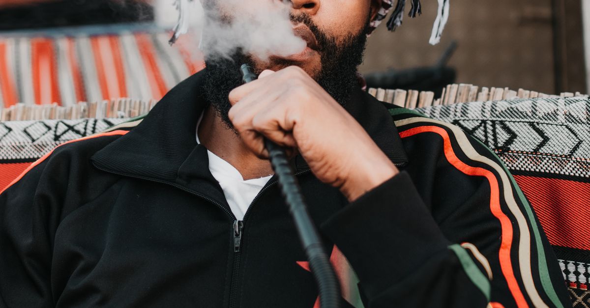Using Shesha Man Using Shisha while Looking at Phone · Free Stock Photo