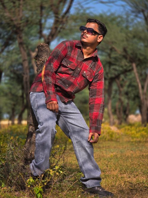 Free Casual portrait of a man leaning on a tree in a sunny forest Stock Photo