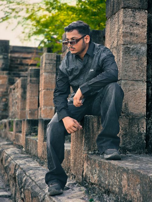 Free A man in sunglasses sitting on ancient stone steps outdoors, exuding a thoughtful mood. Stock Photo