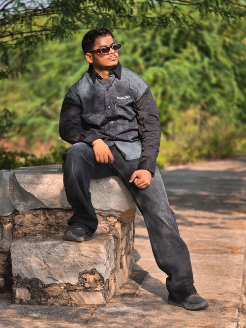 Free Man in casual wear relaxing on stone bench outdoors on a sunny day. Stock Photo