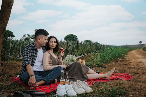 Man And Woman Sitting On Red Textile Having A Picnic