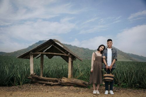 Free A couple poses playfully by a rustic structure on a farm in Ninh Bình, Vietnam, with mountains in the background. Stock Photo