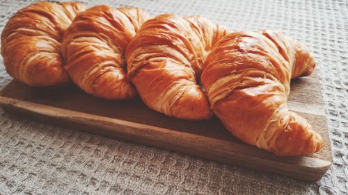 Free Golden brown croissants displayed on a rustic wooden board. Stock Photo
