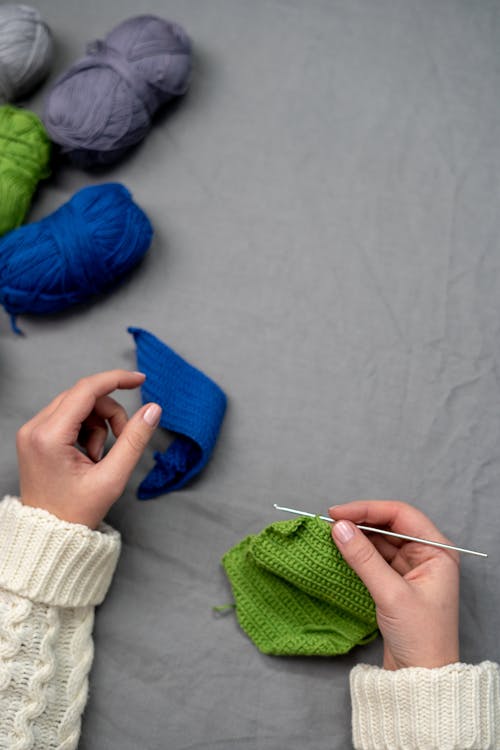 Person Holding Blue Textile and White Yarn