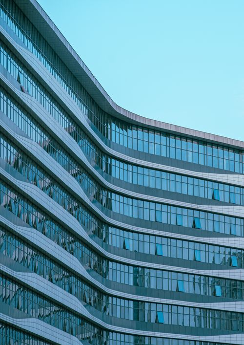 Free Sleek modern office building with reflective glass windows under a clear blue sky. Stock Photo