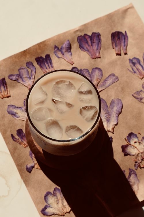 Free Iced coffee on floral background with purple petals under soft lighting. Stock Photo