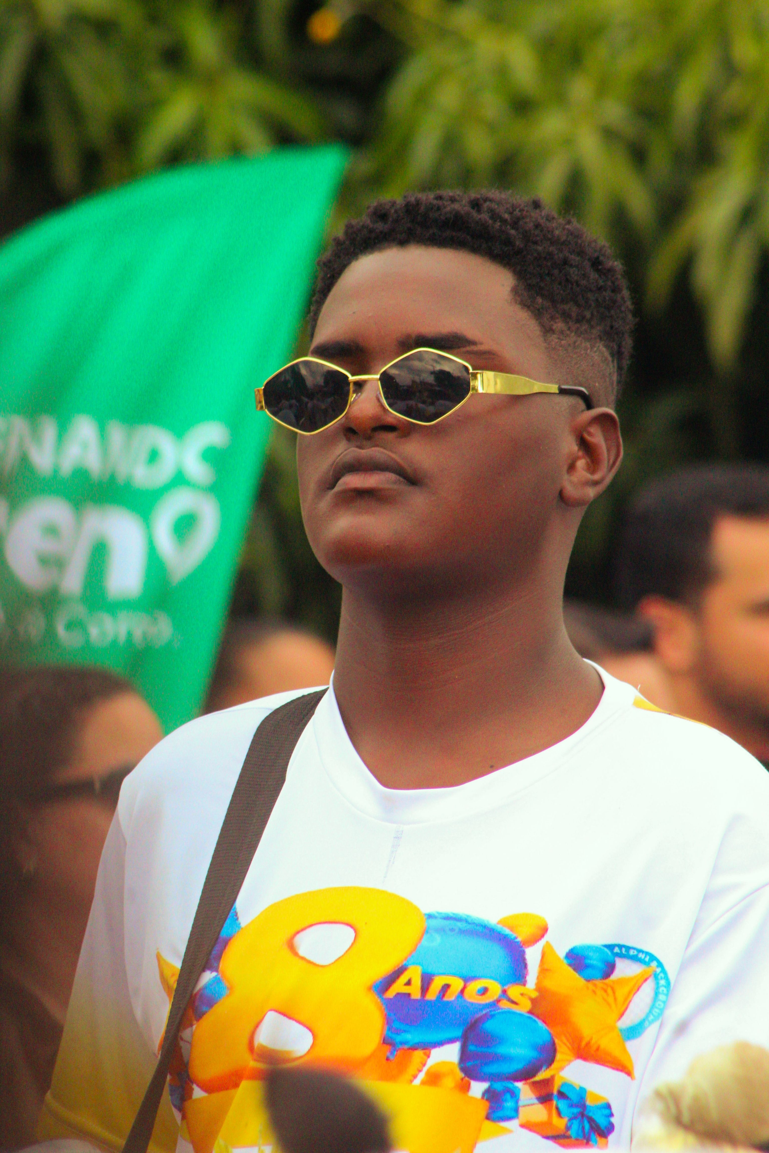 Teenager wearing sunglasses attending a lively outdoor event.