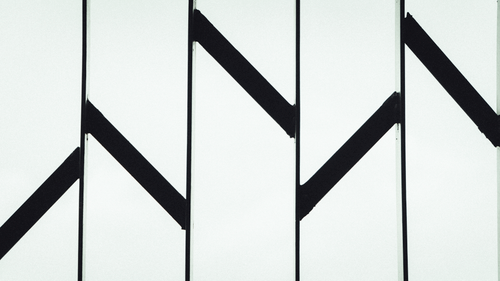 Free A modern abstract design featuring a black zigzag pattern on a glass facade, creating a minimalist effect. Stock Photo