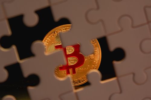 Free A bitcoin coin partially obscured by puzzle pieces, symbolizing the complexity and mystery of cryptocurrency. Stock Photo