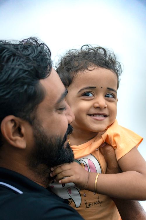 Free A joyful father holding his smiling young daughter with a warm expression. Stock Photo