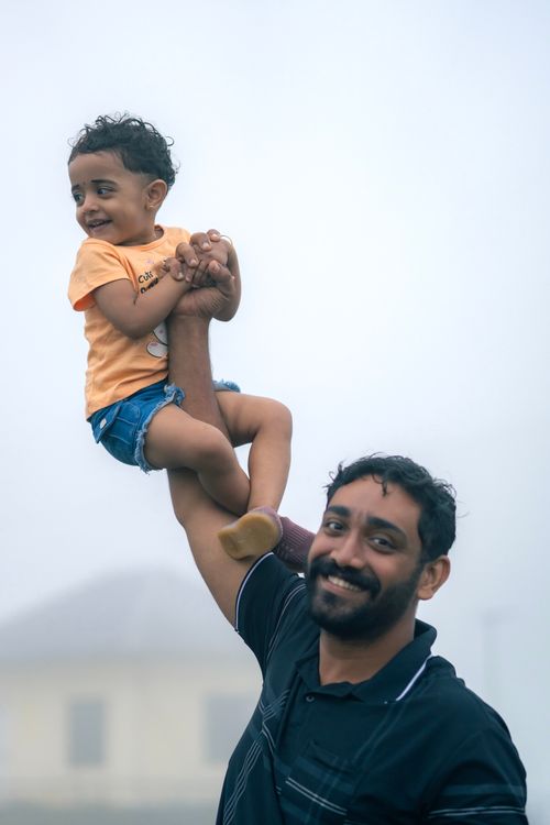 Free Joyful moment of a father lifting his smiling child in the misty outdoors, capturing a playful and loving bond. Stock Photo