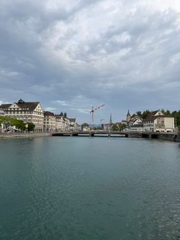 Beautiful view of Limmat River with Zurich architecture and cloudy sky.