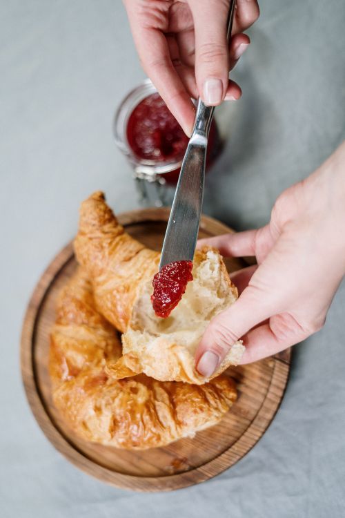 Free Enjoy a delicious breakfast with croissants and jam in a cozy setting. Stock Photo