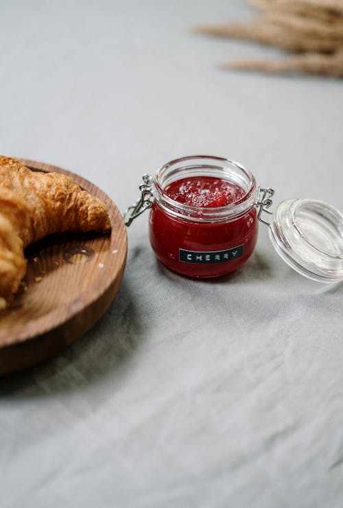 Bread on Brown Wooden Round Plate Beside Clear Glass Jar