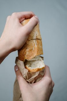从袋子里撕下一块新鲜的小麦面包，双手捧着，给人一种乡村和自制的感觉