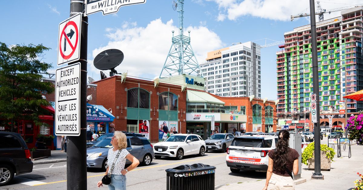 Street scene in ByWard Market, Ottawa featuring pedestrians, traffic, and city architecture.