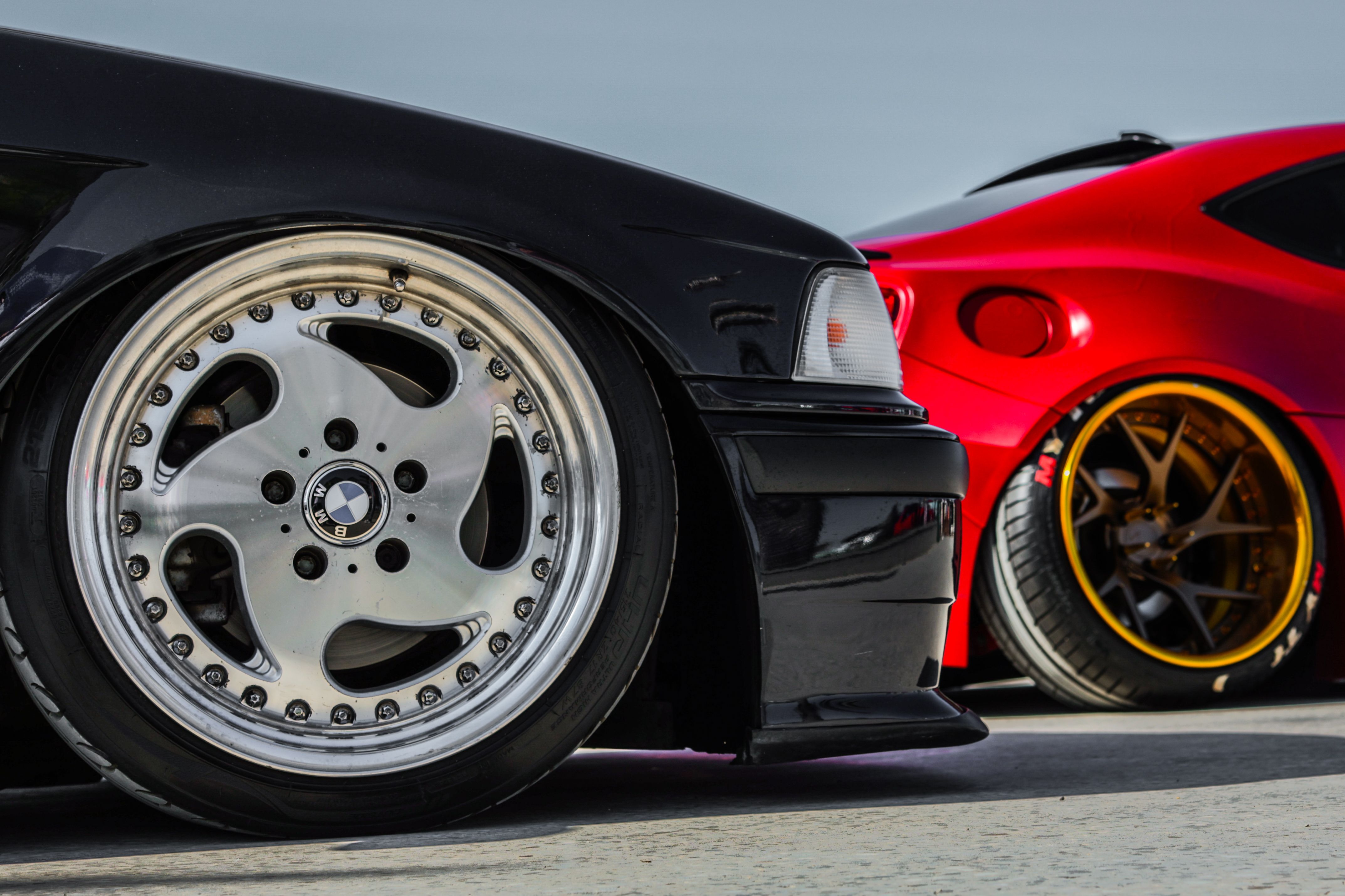 Close-up of the wheels of two modified sports cars with custom rims
