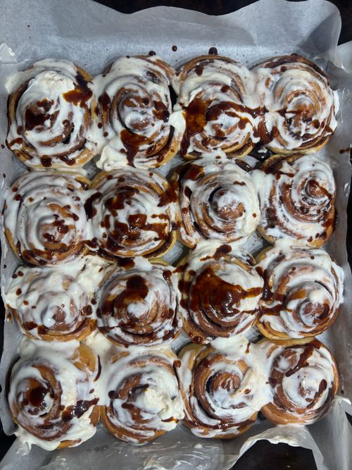 Free Delicious homemade cinnamon rolls topped with creamy frosting and chocolate drizzle, perfect for breakfast or dessert. Stock Photo