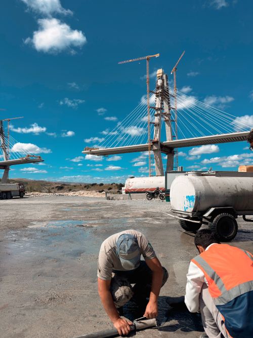 Free Workers inspecting bridge construction under a bright blue sky. Stock Photo