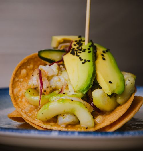 Free Close-up of a seafood tostada topped with avocado, cucumber, and black sesame seeds. Stock Photo