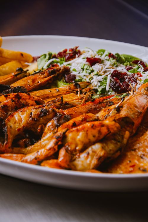 Free Delicious grilled prawns with fresh salad on a plate, perfect for seafood lovers. Stock Photo