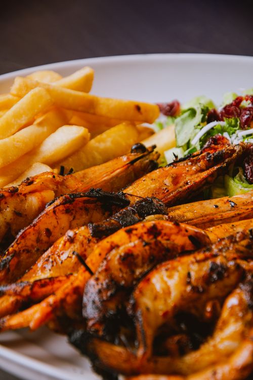 Free Delicious grilled shrimp served with crispy fries and fresh salad on a plate. Stock Photo