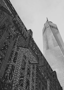 Striking black-and-white angle of One World Trade Center with urban street art in New York City.