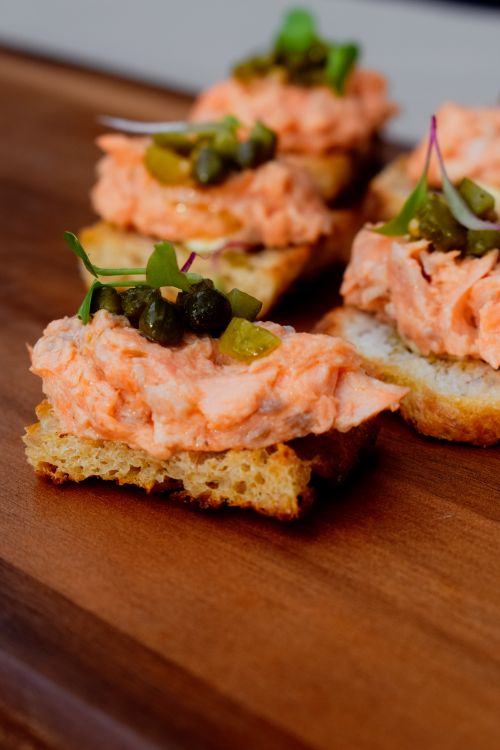 Free Appetizing salmon crostini topped with capers, garnished with microgreens on a wooden board. Stock Photo