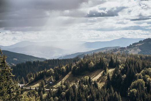 Breathtaking view of a mountain forest with sunbeams through the clouds.
