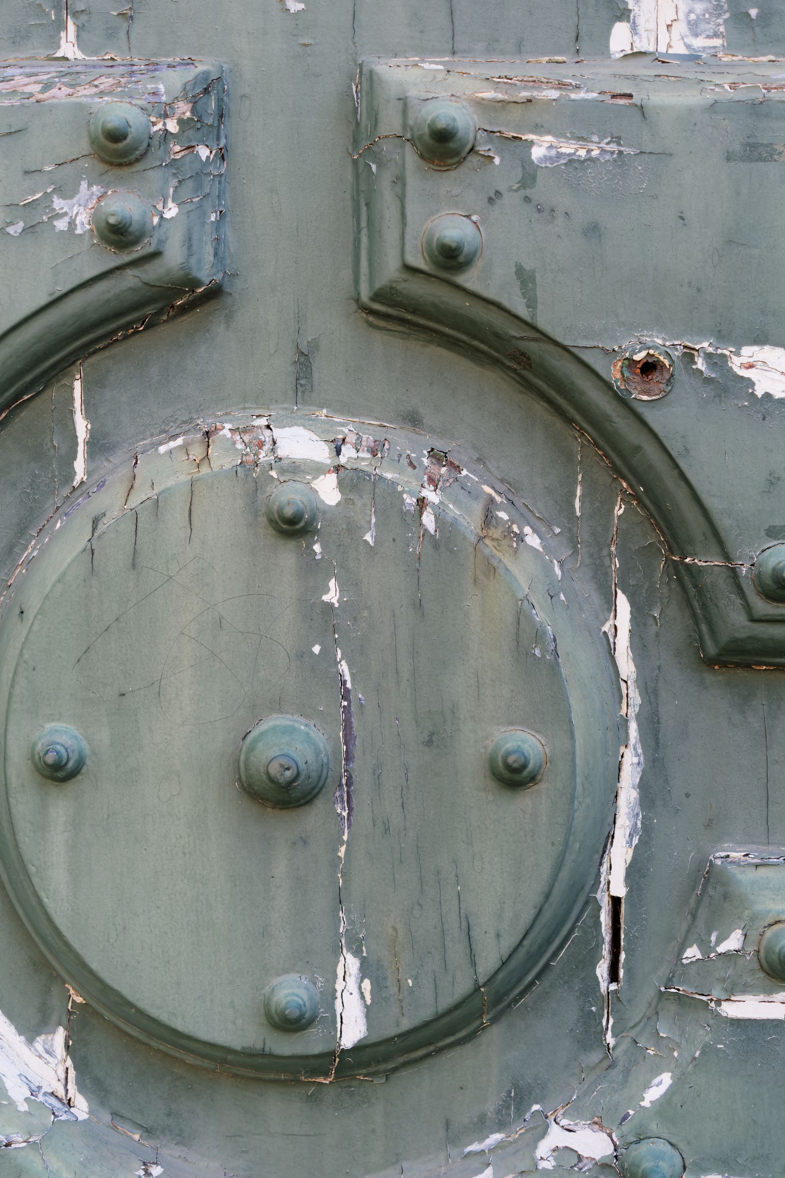 Gros plan sur une porte ancienne patinée, rivets et peinture écaillée