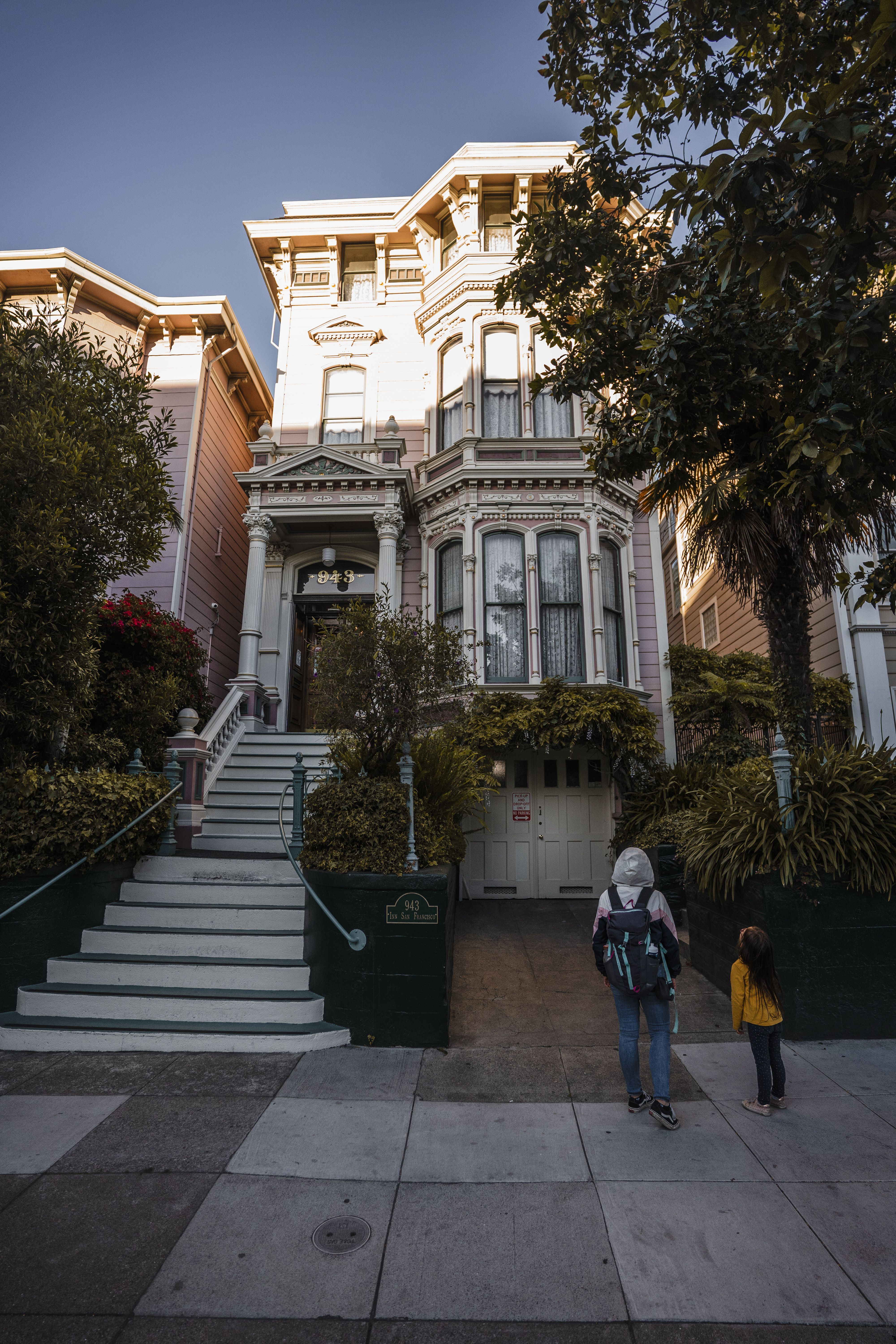 Charming Victorian house facade with two people walking by on a sunny day - neighborhood history for realtors