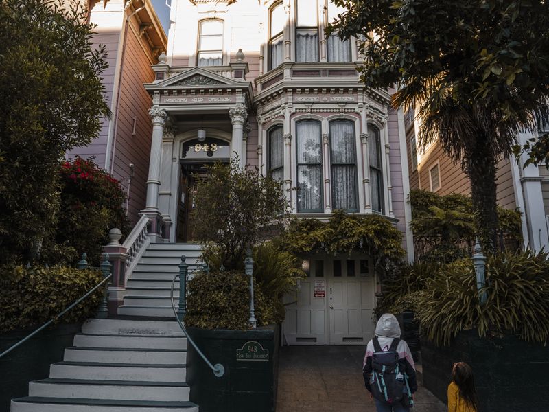Charming Victorian house facade with two people walking by on a sunny day - neighborhood history for realtors