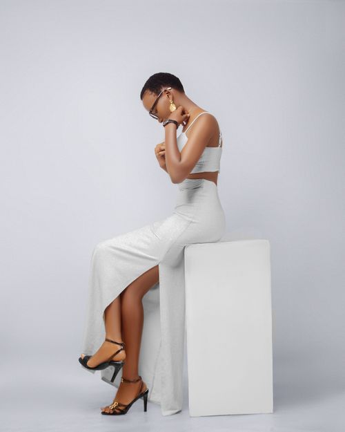 Free Fashionable woman in white dress seated on stool, side profile. Stock Photo