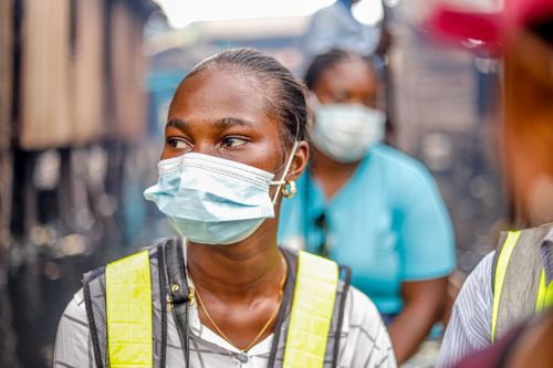 Free Women wearing protective masks and safety vests, working outdoors in urban setting. Stock Photo