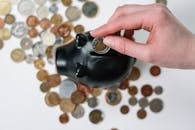 Person Putting Coin in a Piggy Bank
